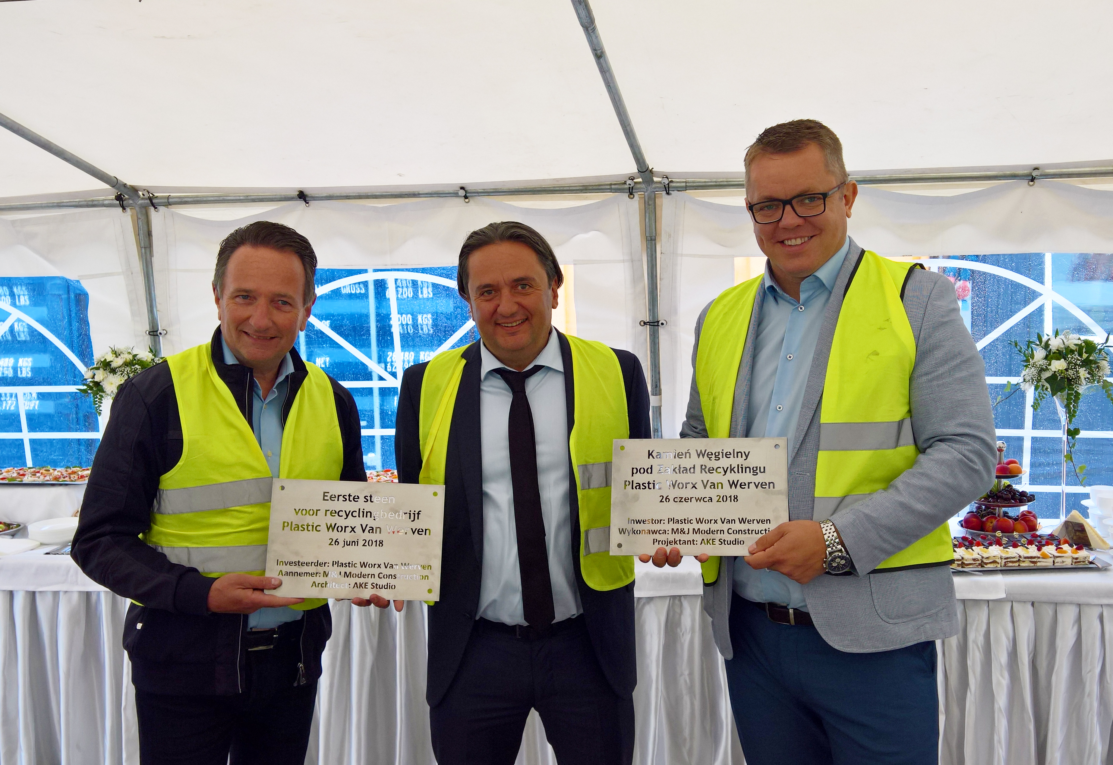 Drie bestuurders tonen de eerste-steen-plaquettes van Plastic Worx Van Werven in Polen