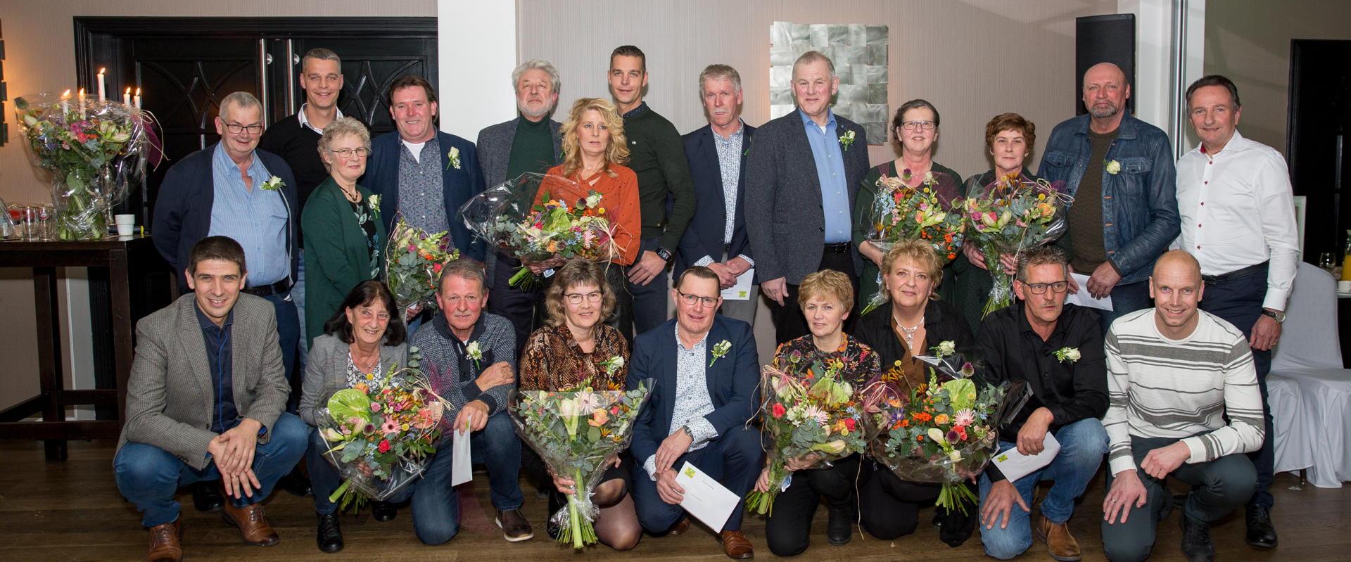 Groepsfoto van de gepensioneerde en jubilerende medewerkers met bloemen