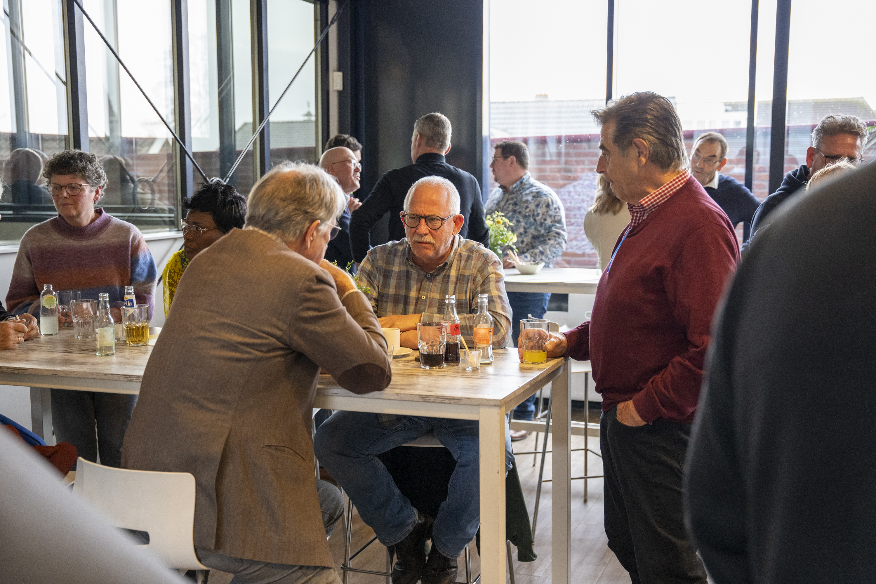Genodigden in gesprek aan een statafel met frisdrank en bier tijdens de nieuwjaarsbijeenkomst