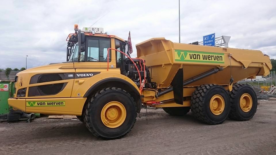 De knikdumper ECO 6x6 van opzij langs de weg, met het verkeersbord Muiden/Weesp op de achtergrond