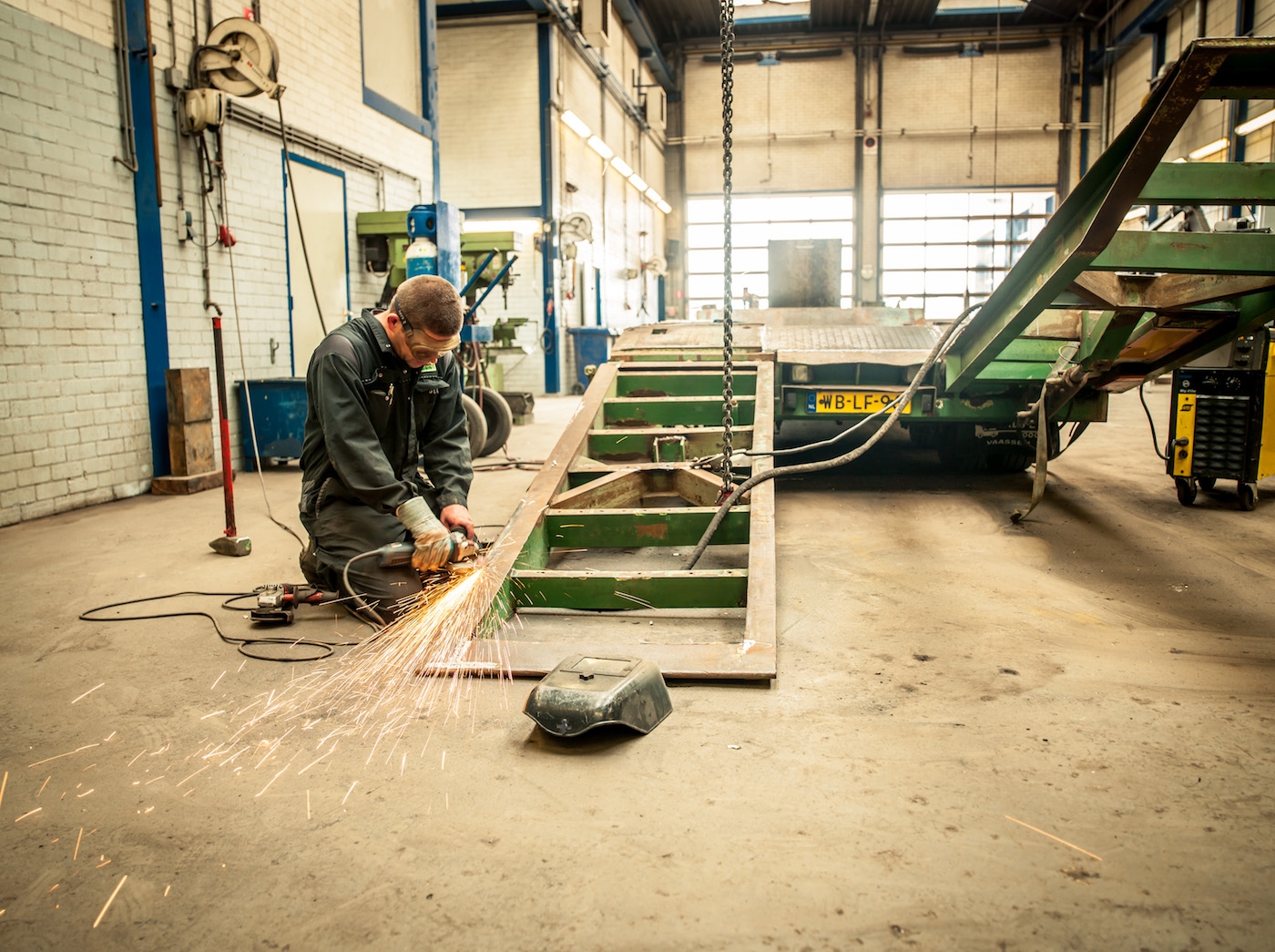 Monteur slijpt aan het chassis van een oplegger in de werkplaats