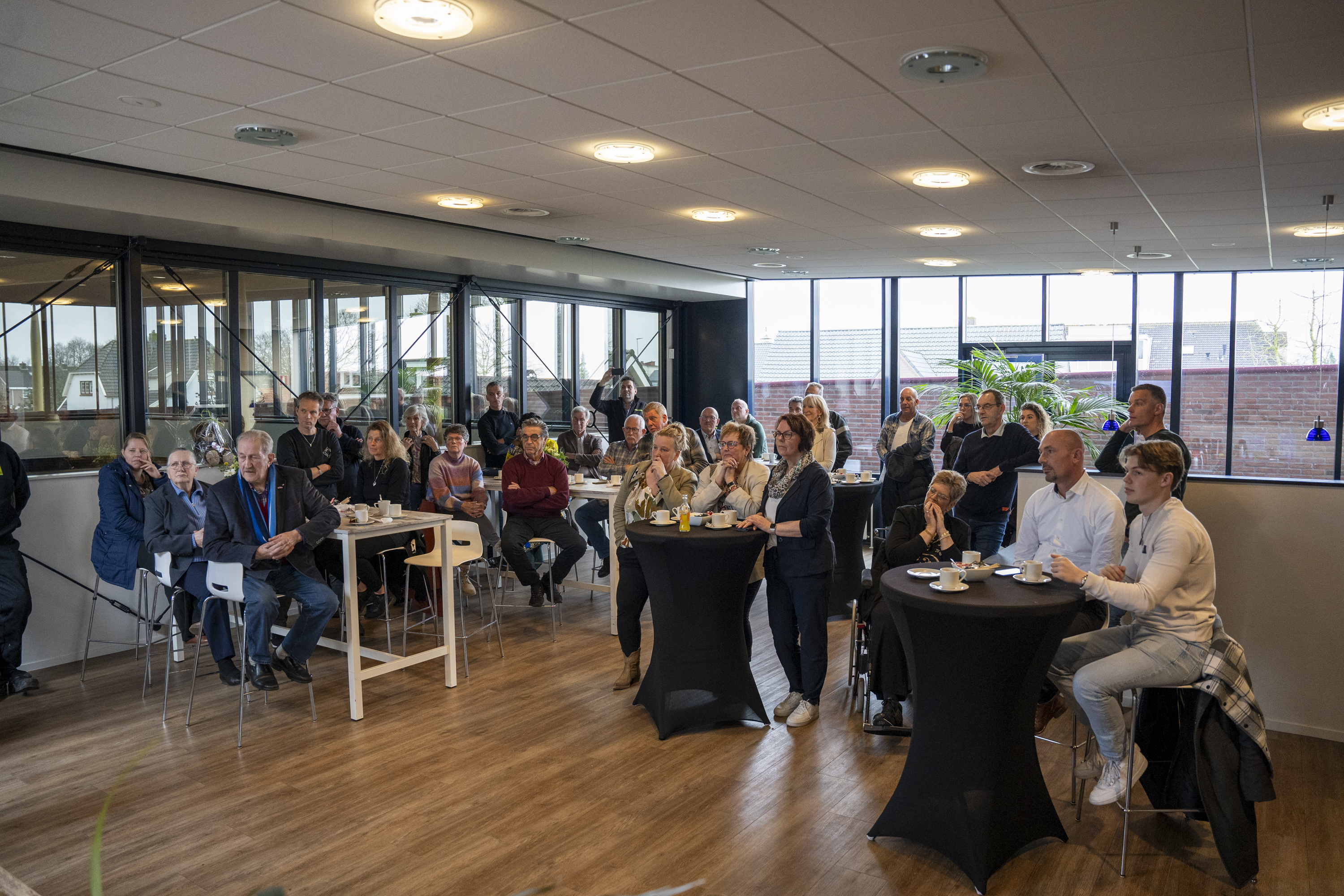 Genodigden van de goede doelen luisteren aan statafels en tafels met koffie in de ontvangstruimte